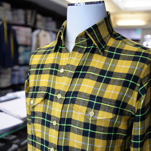 A yellow, black and green flannel check sport shirt with two pockets, showcased on a mannequin.